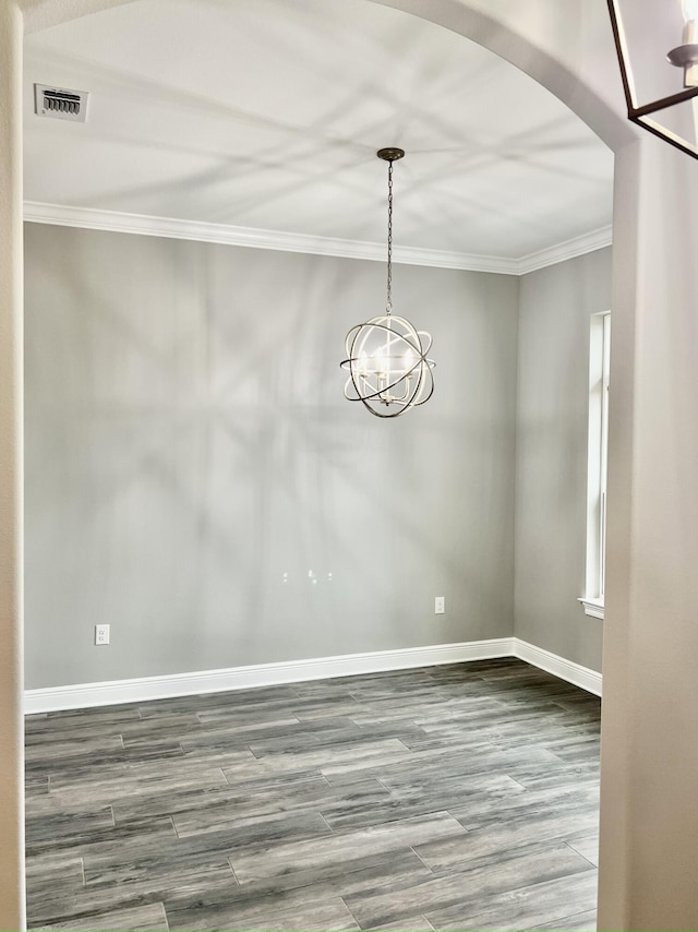 unfurnished room with an inviting chandelier, crown molding, and wood-type flooring