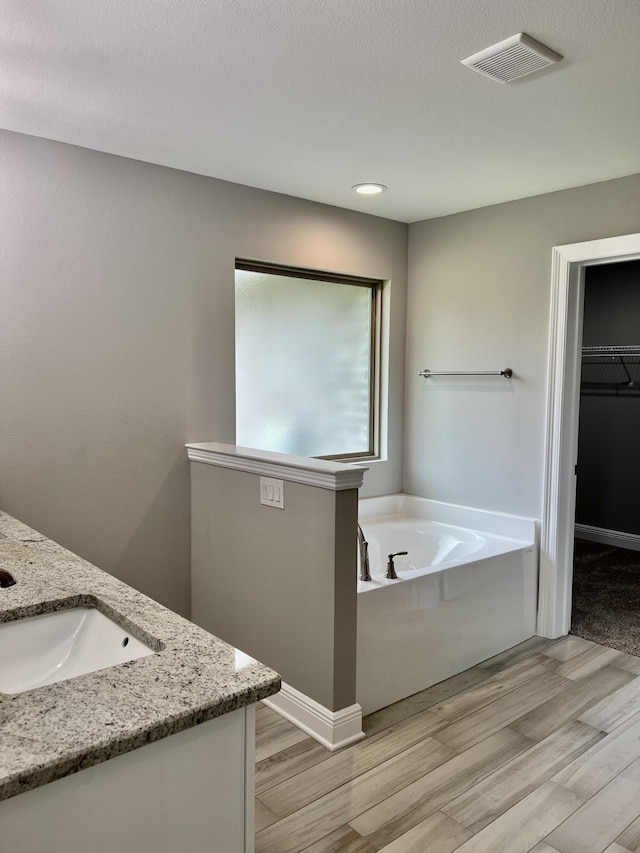 bathroom featuring hardwood / wood-style floors, a washtub, and vanity