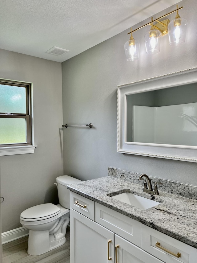 bathroom featuring a textured ceiling, hardwood / wood-style floors, vanity, and toilet