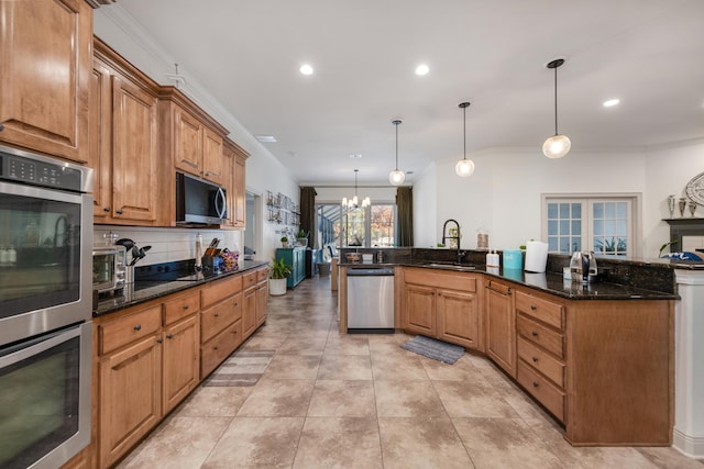 kitchen featuring backsplash, a chandelier, ornamental molding, stainless steel appliances, and a sink