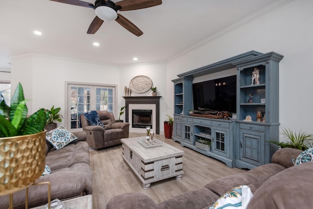 living room with crown molding, recessed lighting, a fireplace, and light wood-style floors