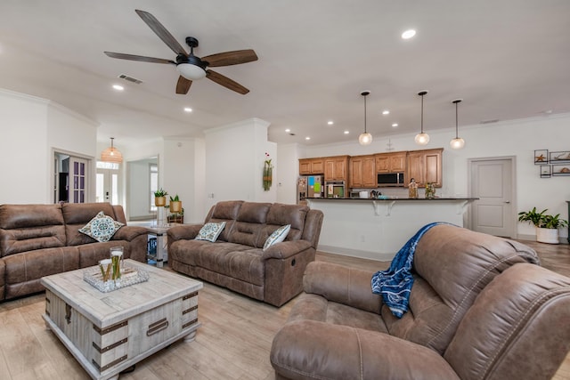 living area featuring visible vents, light wood-style floors, and ornamental molding