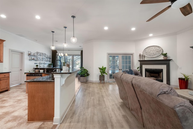 kitchen with dishwashing machine, a brick fireplace, open floor plan, and ornamental molding