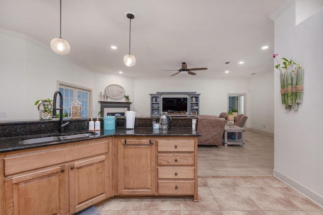 kitchen with dark stone counters, ornamental molding, a sink, pendant lighting, and open floor plan