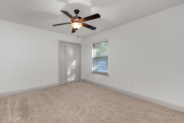 spare room with baseboards, carpet, and a ceiling fan