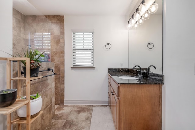 bathroom with tile patterned floors, baseboards, walk in shower, and vanity