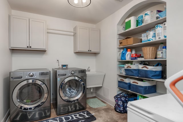 clothes washing area featuring cabinet space, baseboards, and washing machine and clothes dryer