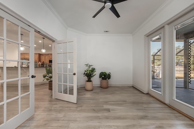 doorway featuring light wood finished floors, visible vents, baseboards, ornamental molding, and french doors