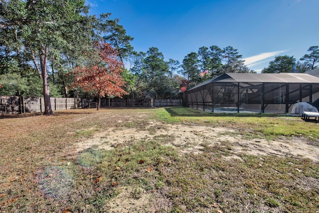 view of yard featuring glass enclosure, a pool, and a fenced backyard