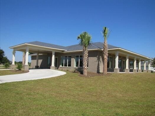 back of house featuring concrete driveway and a yard