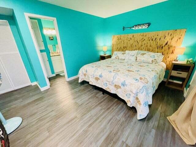 bedroom with ensuite bathroom and dark wood-type flooring