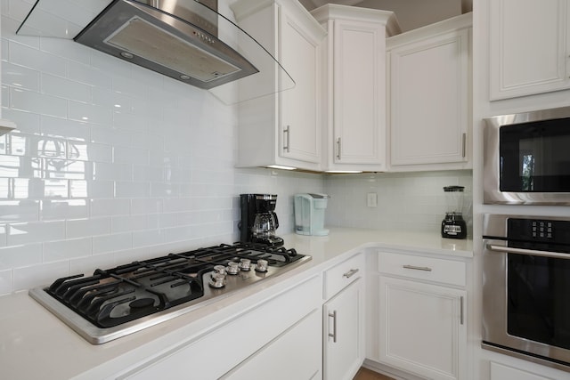 kitchen with backsplash, white cabinetry, appliances with stainless steel finishes, and wall chimney exhaust hood