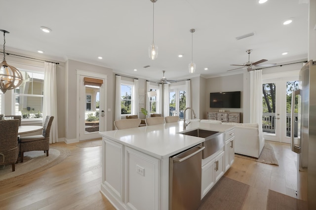 kitchen featuring white cabinetry, light hardwood / wood-style flooring, hanging light fixtures, an island with sink, and stainless steel appliances