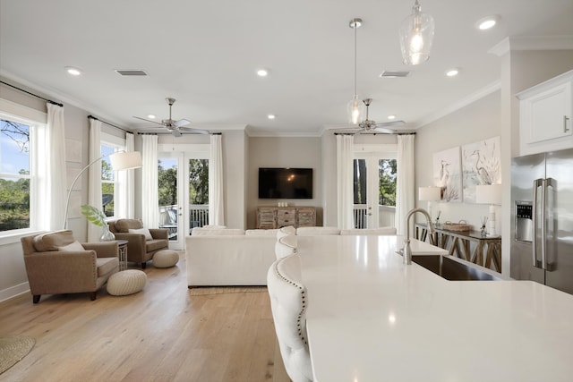 kitchen with decorative light fixtures, sink, stainless steel fridge with ice dispenser, ornamental molding, and light hardwood / wood-style flooring