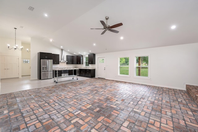 unfurnished living room featuring ceiling fan with notable chandelier and high vaulted ceiling