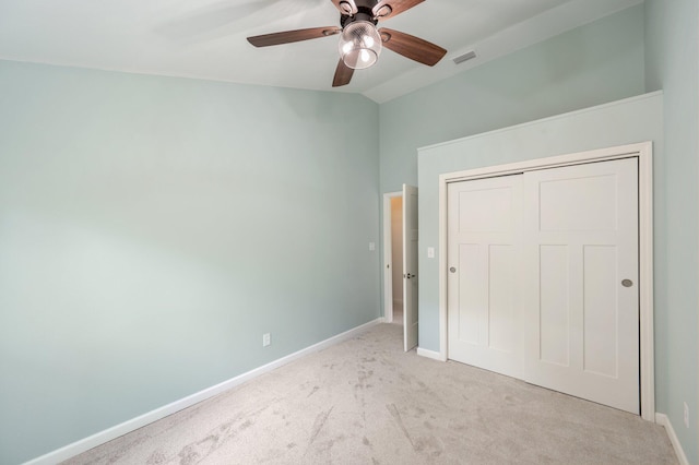 unfurnished bedroom featuring ceiling fan, light colored carpet, a closet, and lofted ceiling