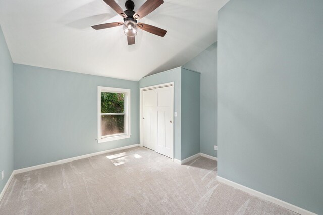 unfurnished bedroom featuring a closet, ceiling fan, vaulted ceiling, and light colored carpet