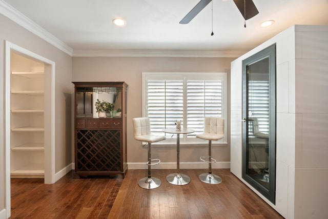 living area featuring crown molding, dark wood-type flooring, built in features, and ceiling fan