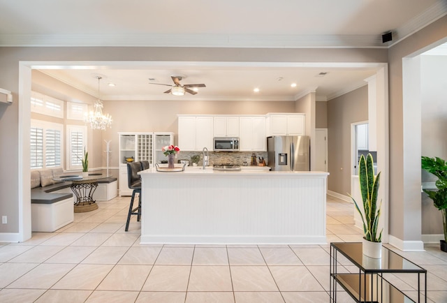 kitchen featuring light tile patterned floors, appliances with stainless steel finishes, an island with sink, and white cabinets