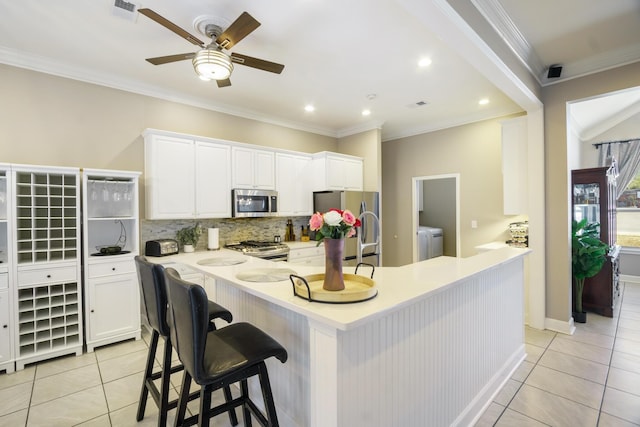 kitchen with separate washer and dryer, light tile patterned flooring, a breakfast bar, and appliances with stainless steel finishes