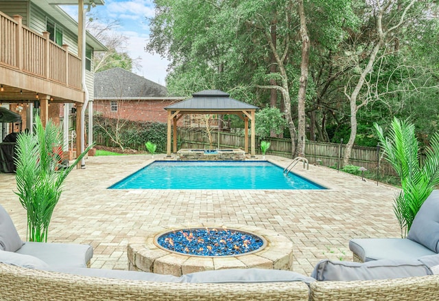 view of pool with a gazebo, a patio area, and an outdoor living space with a fire pit