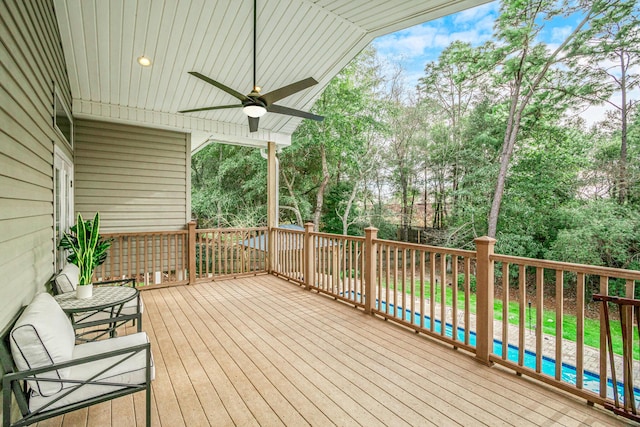 wooden deck featuring a pool and ceiling fan