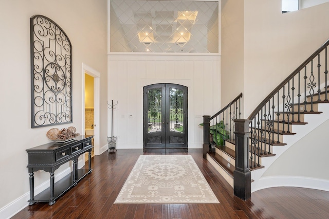 foyer featuring french doors, a towering ceiling, and dark hardwood / wood-style floors