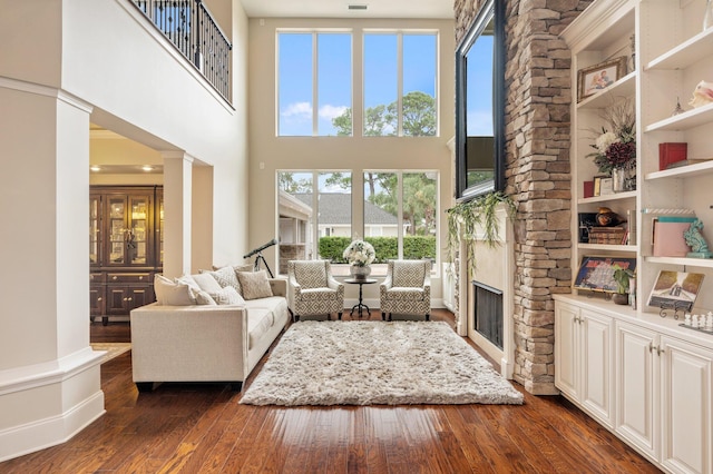 living room with a fireplace, built in features, a healthy amount of sunlight, and dark hardwood / wood-style floors