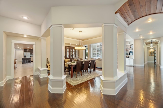 interior space with hardwood / wood-style flooring, built in features, and ornate columns