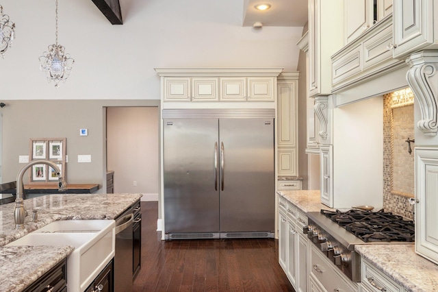 kitchen with appliances with stainless steel finishes, light stone countertops, sink, and beam ceiling