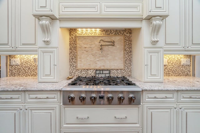 kitchen featuring light stone counters, white cabinetry, stainless steel gas stovetop, and decorative backsplash