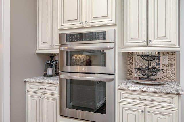 kitchen with double oven, tasteful backsplash, and light stone counters