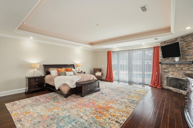 bedroom with a fireplace, a tray ceiling, access to exterior, and dark hardwood / wood-style floors