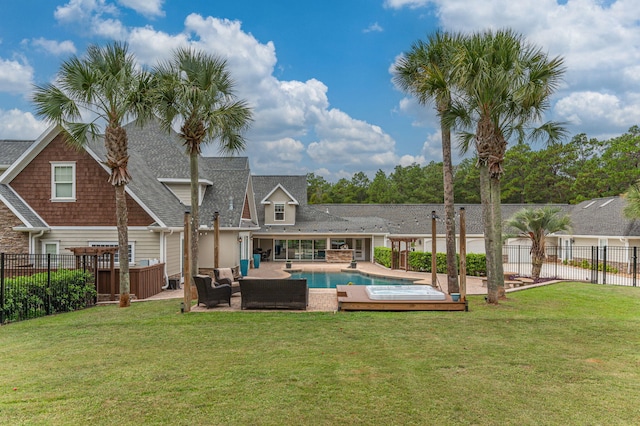 rear view of property featuring a patio area, a yard, a fenced in pool, and an outdoor living space