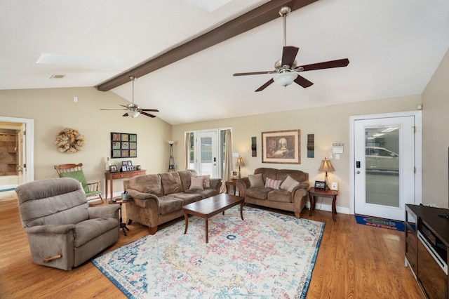 living room with ceiling fan, vaulted ceiling with skylight, and hardwood / wood-style floors