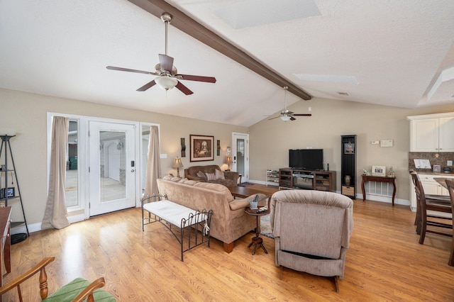 living room with a textured ceiling, ceiling fan, light hardwood / wood-style flooring, and vaulted ceiling with beams