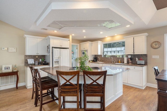 kitchen with a kitchen bar, white cabinets, a center island, and paneled built in fridge