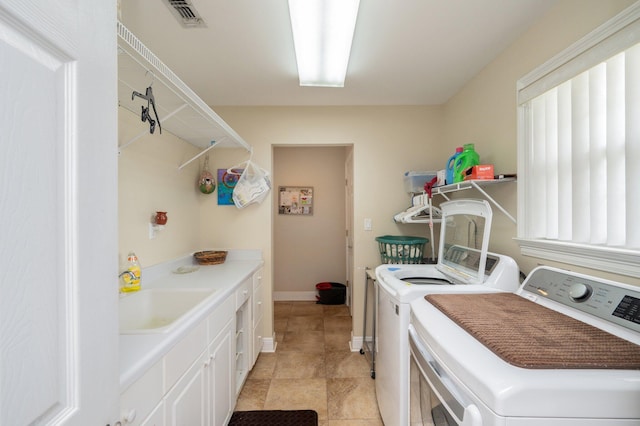 clothes washing area with sink, cabinets, and washer and clothes dryer