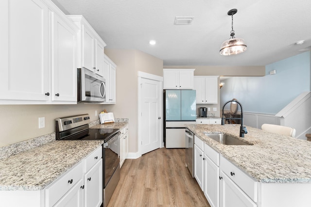 kitchen featuring white cabinets, sink, appliances with stainless steel finishes, and an island with sink