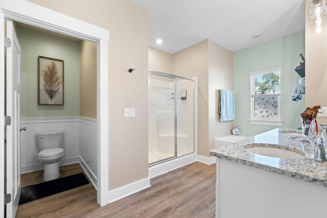 bathroom featuring toilet, hardwood / wood-style flooring, a shower with door, and vanity