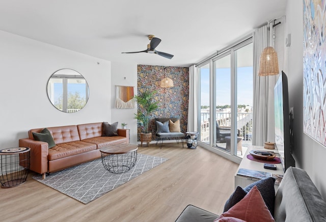 living room with a wall of windows, light hardwood / wood-style floors, and ceiling fan