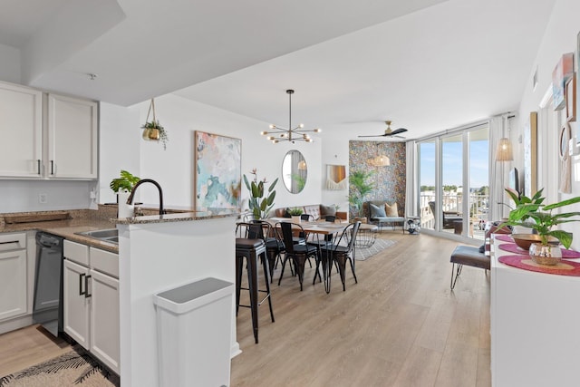 kitchen with sink, white cabinets, expansive windows, light hardwood / wood-style floors, and kitchen peninsula