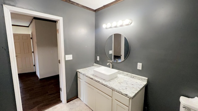 bathroom with toilet, vanity, and ornamental molding