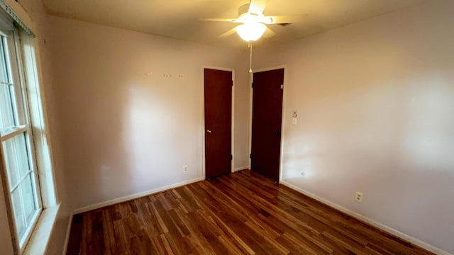 empty room featuring dark wood-type flooring and ceiling fan