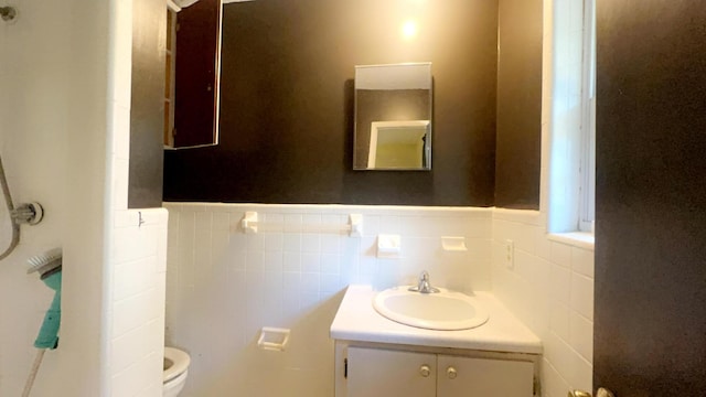 bathroom featuring toilet, tile walls, and vanity