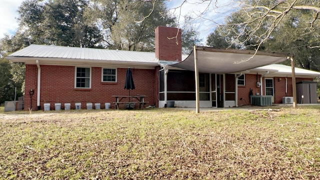 rear view of house with central AC, a yard, and a sunroom