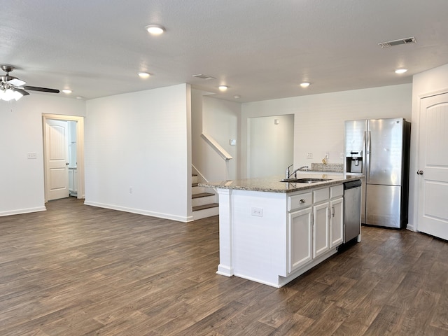 kitchen with sink, a kitchen island with sink, stainless steel appliances, dark hardwood / wood-style floors, and white cabinets