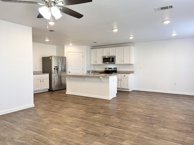 kitchen with white cabinetry, appliances with stainless steel finishes, a kitchen island with sink, and dark hardwood / wood-style floors