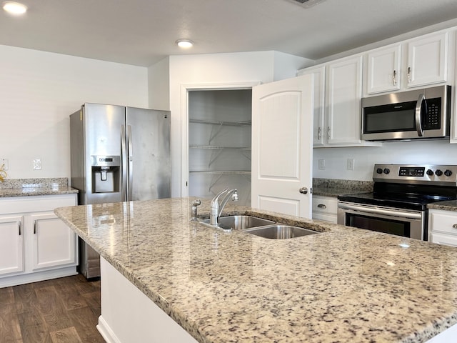 kitchen featuring light stone counters, stainless steel appliances, sink, and a center island with sink