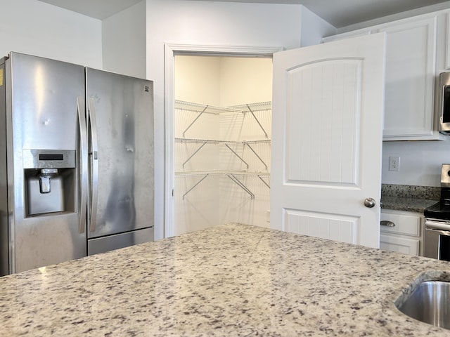 kitchen with white cabinetry, light stone countertops, and stainless steel appliances